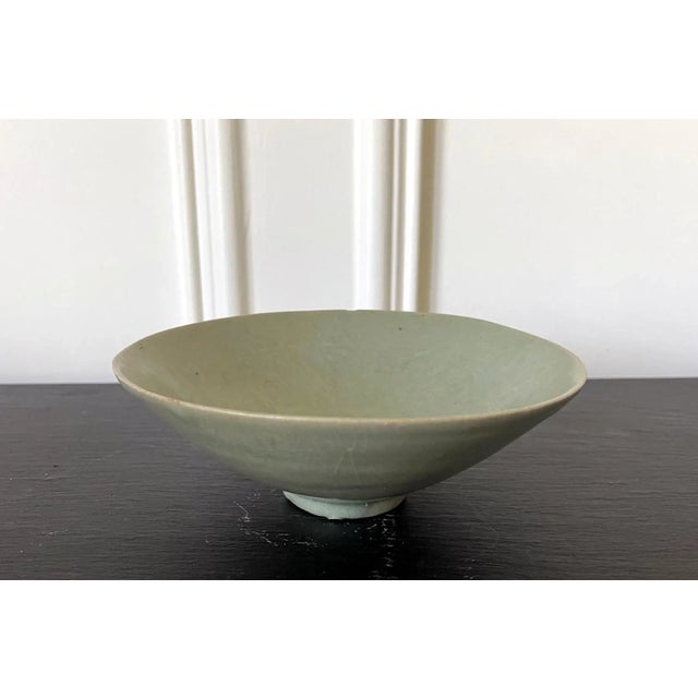 An antique Korean ceramic tea bowl with celadon glaze from Goryeo dynasty, circa 12th century. The thin-walled stoneware...