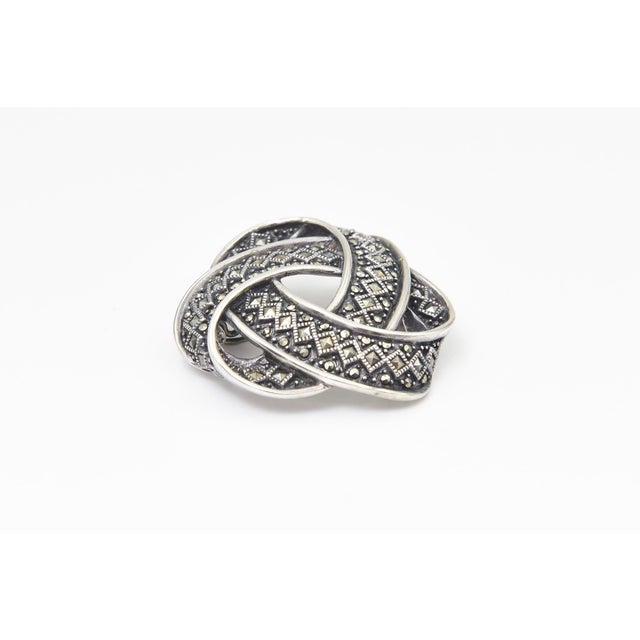 This 20th Century intricate Celtic brooch is crafted in sterling silver. It features an interwoven knot design with...