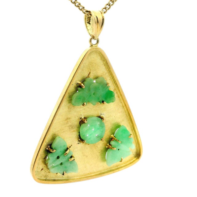 A beautiful vintage pendant featuring carved jade set in 14-karat yellow gold. The design is composed of three jade...
