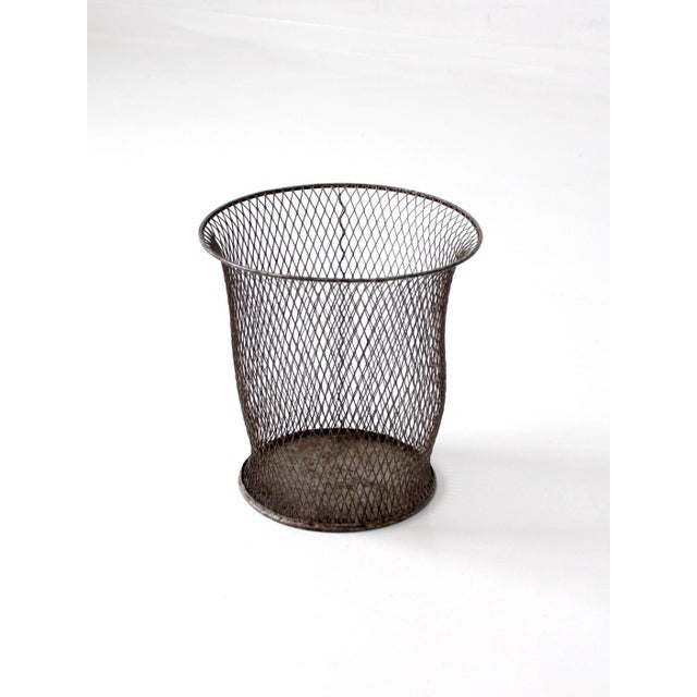 An early 20th century industrial wire waste basket with a softly tapered form and rolled rim. The open mesh construction...
