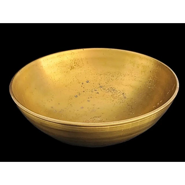 Offered is a sleek and heavy brass bowl with a blackened patina swirl detail on the exterior by Calvin Klein. The exterior...