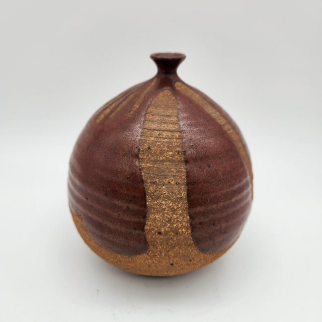 Globular stoneware weed pot with oxblood glaze over exposed sandy clay body, combed vertical striations, flared miniature...