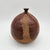 Globular stoneware weed pot with oxblood glaze over exposed sandy clay body, combed vertical striations, flared miniature...