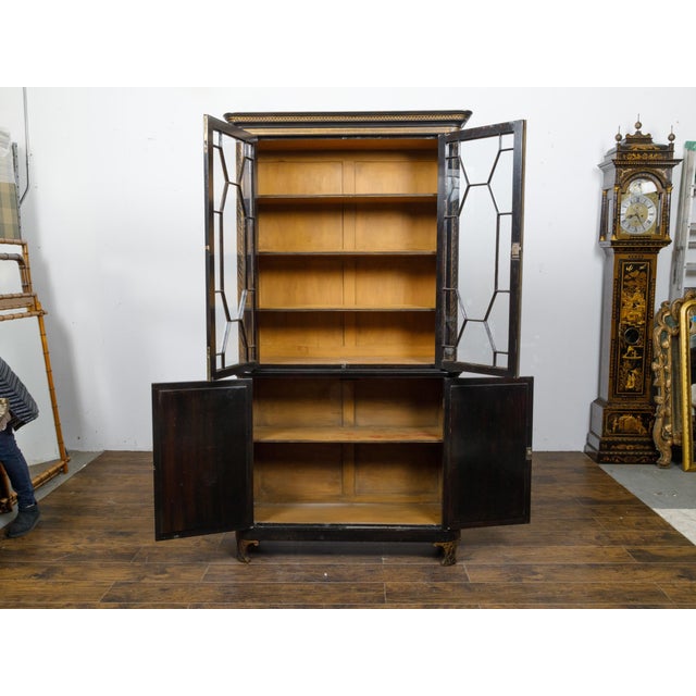 An English black and gold bookcase from the 19th century with Chinoiserie décor and glass doors. This exquisite English...