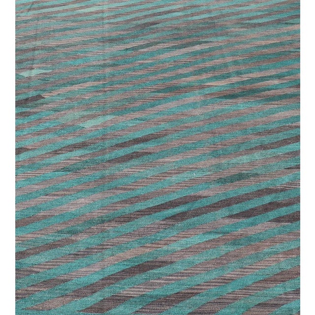 This flat-weave Kilim has been hand-woven. The rug features a modern slanted stripe design, rendered in green and shades...