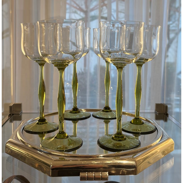 These particularly beautiful Art Nouveau wine glasses have a wavy and curved colorless bowl and a domed green stem.
