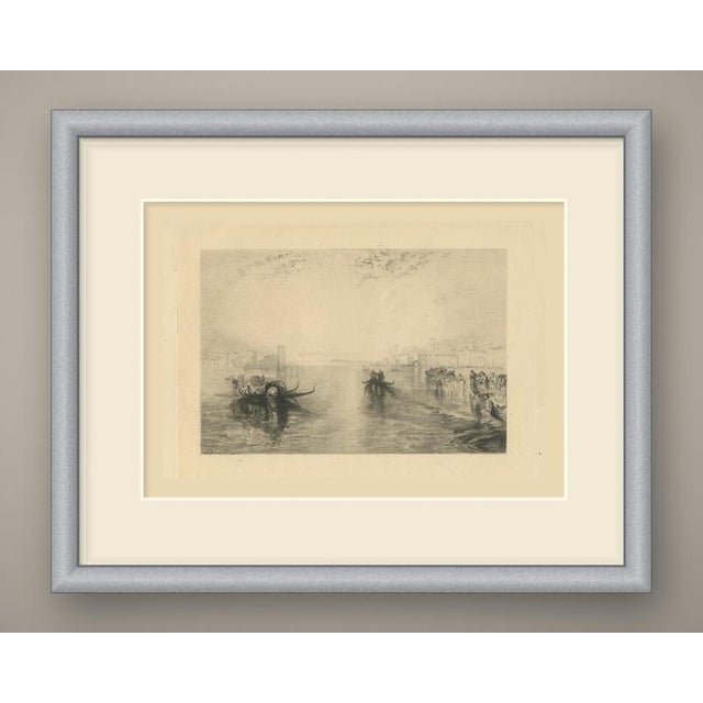 A wide, hazy view across the lagoon at venice. Gondolas glide over still water toward the viewer, the nearest with its...