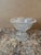 An elegant vintage cut crystal pedestal bowl showcasing intricate floral and starburst motifs throughout. The scalloped...