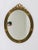 A beautiful and decorative oval gilt wood wall mirror in the Neoclassical style, dating from the early 1900s. The frame is...