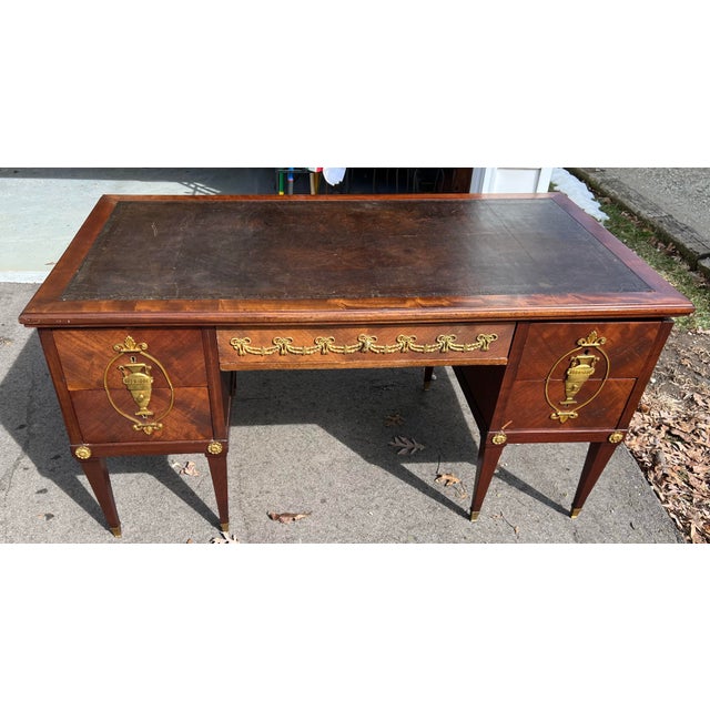 Elegant French Neoclassical-style writing desk featuring a rich mahogany case with inset tooled leather top and finely...