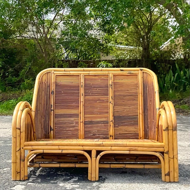 A striking vintage Coastal loveseat. A chic 1950s design made in a tortoise shell pencil reed. Coordinating chair also...