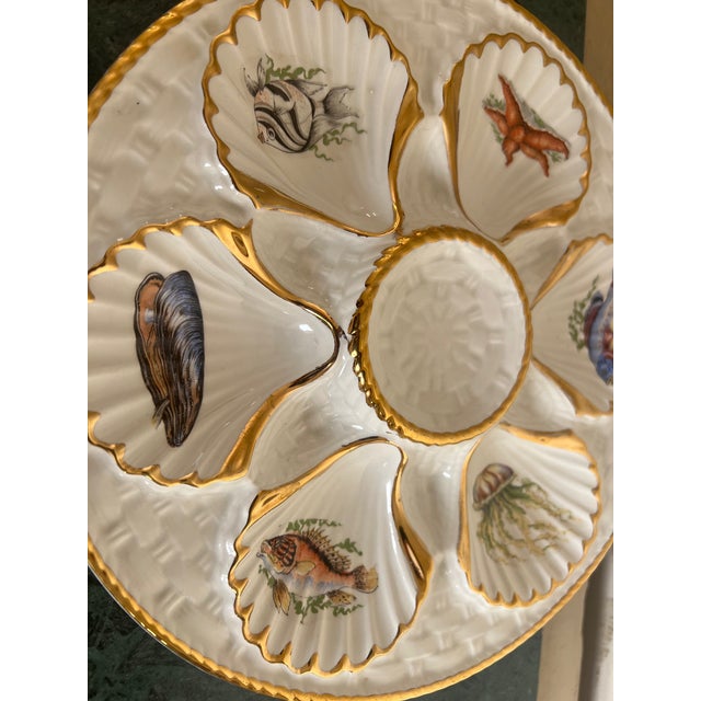 Ceramic oyster / seafood plate includes six wells each with a different sea creature lined in gold paint. The center well...