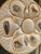 Ceramic oyster / seafood plate includes six wells each with a different sea creature lined in gold paint. The center well...