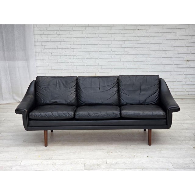 1960s, Danish design by Aage Christensen. 3-seater sofa. Original black furniture leather, teak wood legs. Manufactured by...