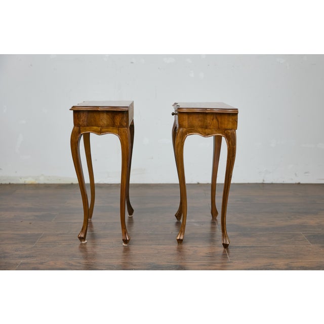 A pair of Italian Louis XV style walnut console tables with serpentine fronts, cabriole legs and single drawers. This...