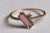A very unusual 14K gold ring featuring an offset, beveled emerald-cut pink tourmaline gemstone at the center with a round,...
