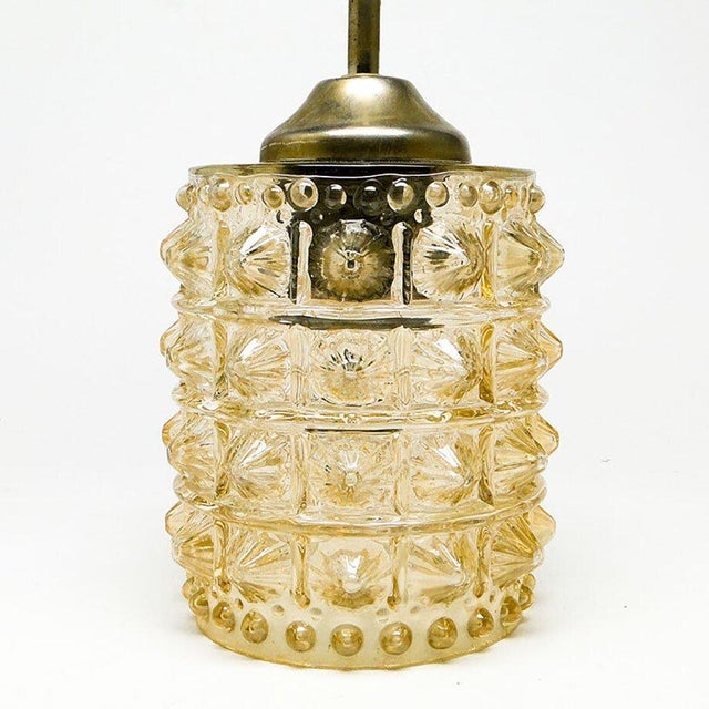 Pendant lamp produced in Poland in the 70s. The design of the lamp is made of brass, and the lampshade is made of glass....