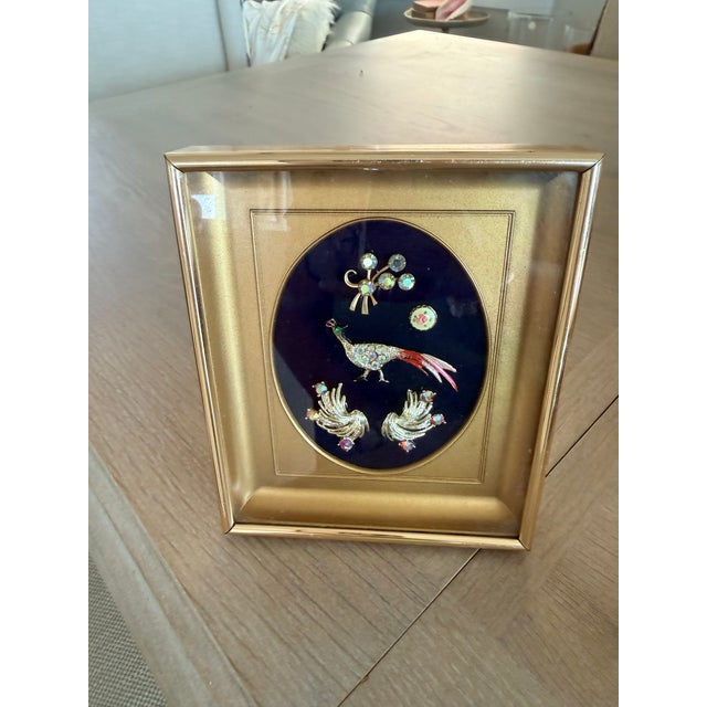 Jewelry from the 1950-60s had been mounted in a frame for display. It appears to be a small rose pin, a set of rhinestone...