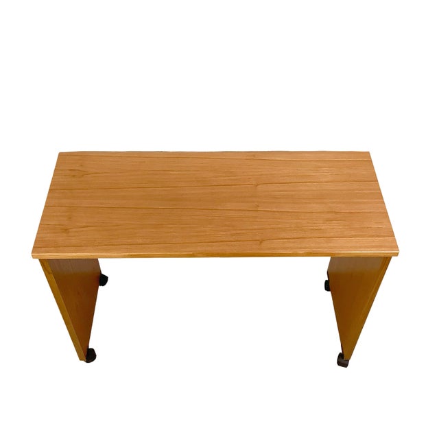 A streamlined vintage teak table combining warm wood grain, compact proportions, and an unusually versatile rolling...