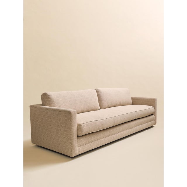 This 1970s sofa features a long, low silhouette with clean arms, a single bench cushion, and two coordinating round...