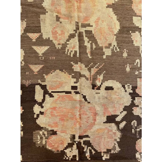 This early 20th century antique flat weave kilim rug, dating to circa 1920, features an elegant large scale floral design...