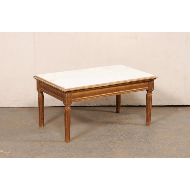 A Swedish wooden coffee table, with white marble top, from the early 20th century. This antique table from Sweden features...