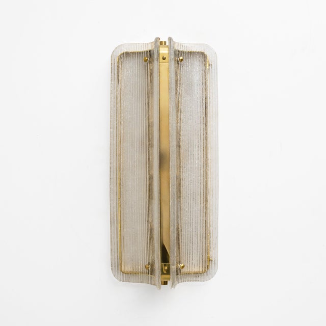 An elegant pair of italian big sconces composed of curved and fluted murano glass panels in a refined shade of clear. The...