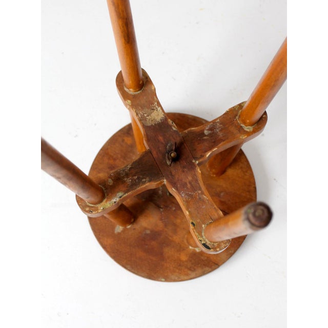 This early 20th-century primitive wood stool, circa 1910s–1930s, features a round plank seat, turned splayed legs, crossed...