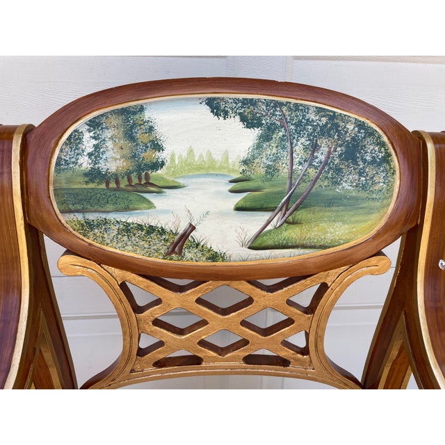 A striking vintage Italian Regency armchair featuring an oval hand-painted landscape medallion, gilt accents, and elegant...