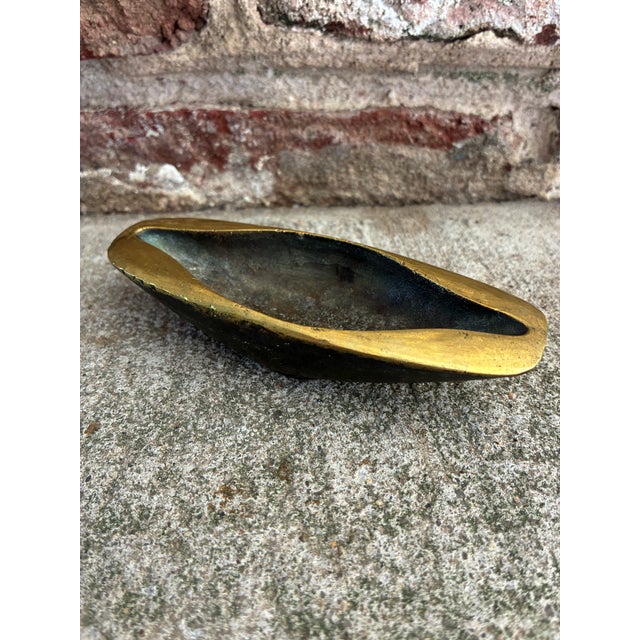 Mid-Century modernist bronze catch-all, highlighted by a polished golden rim that contrasts sharply with its dark body...