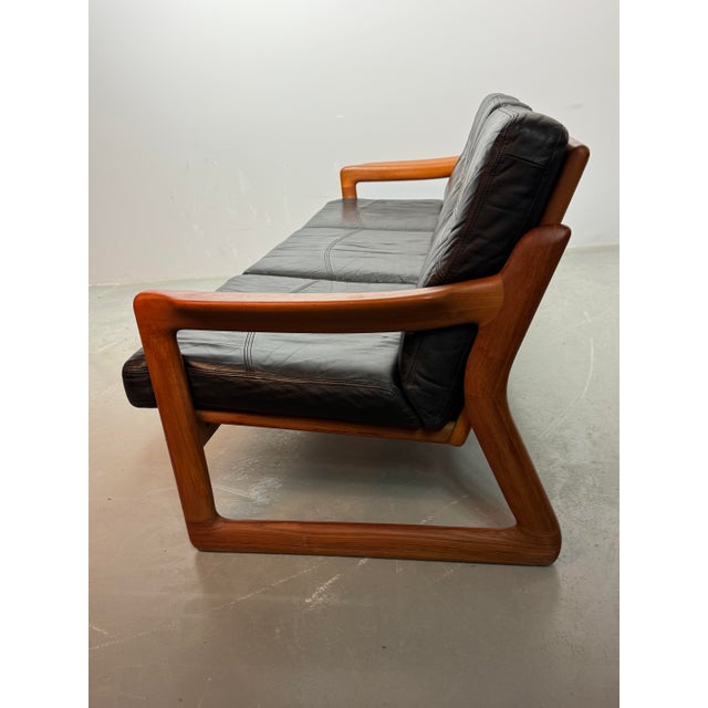Mid-Century Design Komfort Solid Teak Wooden 3-Seat Sofa with Black Leather Cushions Attributed to Sven Ellekaer for...