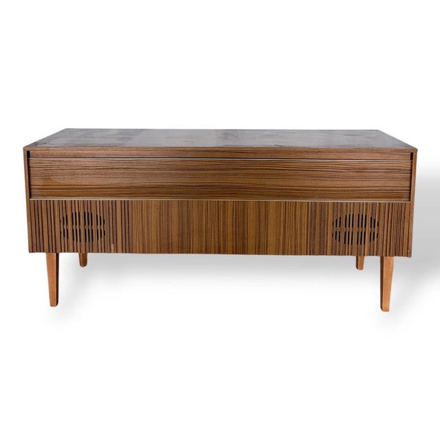 A striking mid-century Marconiphone radiogram, beautifully housed in a sleek wood veneer cabinet with elegant horizontal...