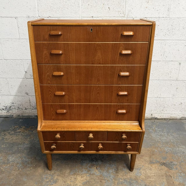 A distinctive Danish high chest dating to the 1940s, with a mix of teak and oak tones, tall case form, and a highly...