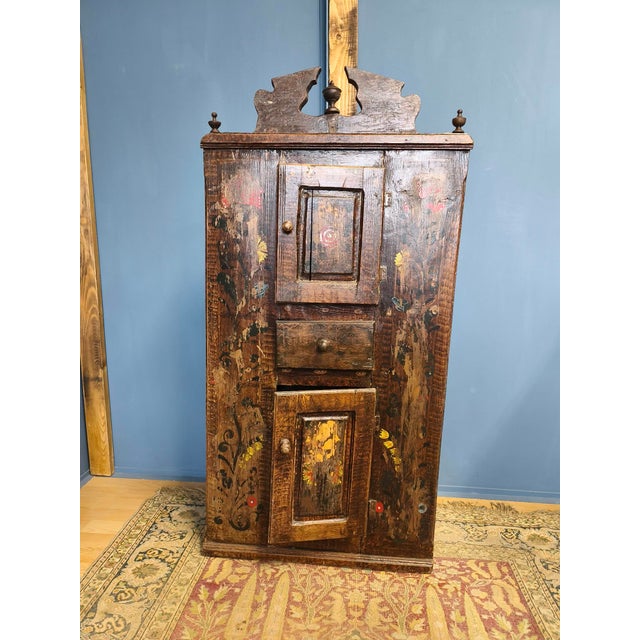 This corner cabinet was made by a country craftsman in the 1850s. It has a simple structure, two doors and a drawer. It...