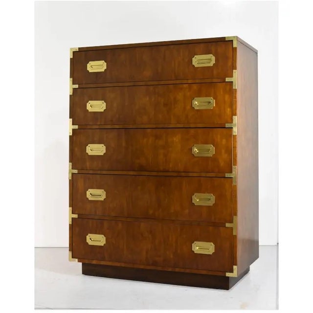 This mid century Campaign highboy dresser by Dixie Furniture has five drawers in a warm, figured brown wood finish. Each...