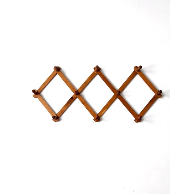 This vintage accordion peg rack features a warm wood finish, turned pegs, and a classic expanding design. The geometric...