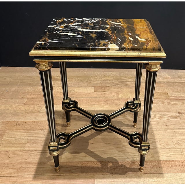 Refined Louis XVI style side table featuring a richly veined marble top set within a molded giltwood and ebonized frame....