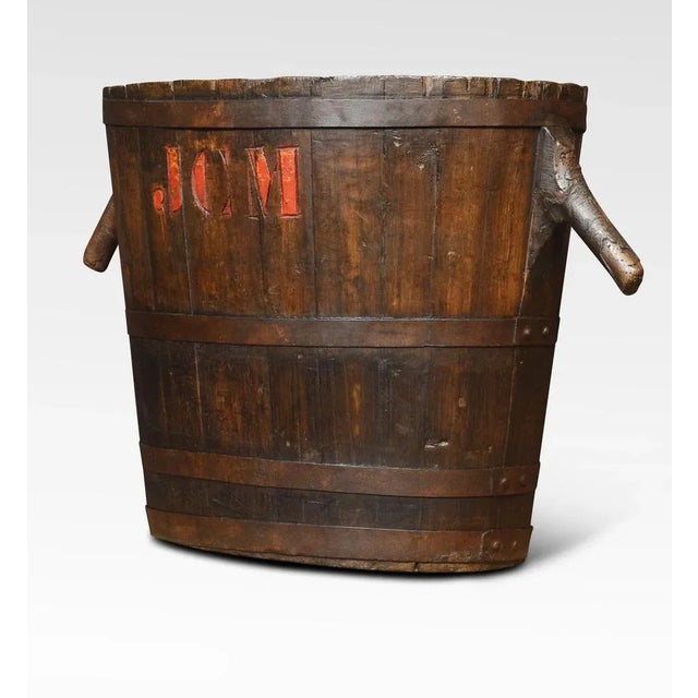 Oval-shaped log bin the oak frame encased in iron bands having stylised handles. Dimensions Height 22 Inches Width 35...