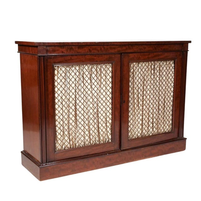 A handsome Regency style mahogany chiffonier featuring two paneled doors inset with decorative latticework, creating an...