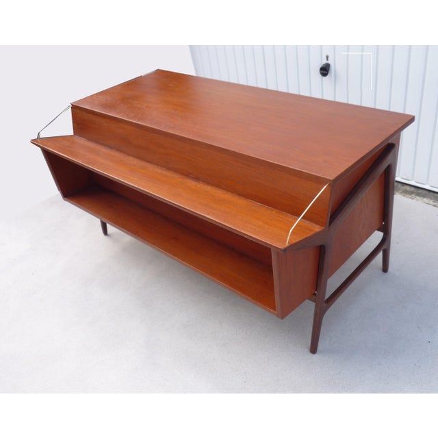 Impressive vintage teak desk in a teak finish. Offset, slanted top with storage: 1 large drawer on the left, 2 drawers on...