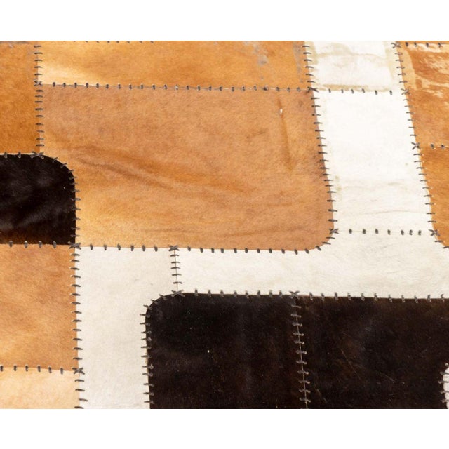 Cowhide Patchwork Carpet, with leather stitching in brown, black, and white. 9' 8" L x 6' 9" W. Provenance: From a 320...