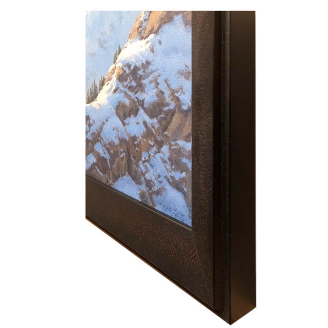 The artwork depicts a serene mountain landscape bathed in the warm glow of afternoon sunlight, highlighting the interplay...