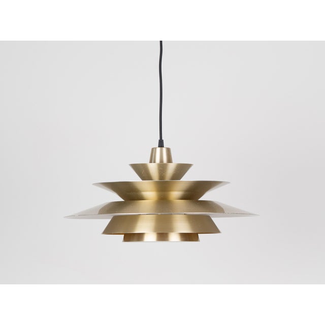 A Scandinavian modernist pendant lamp from the 1960s, crafted from brass with a distinctive multi-layered design. The...