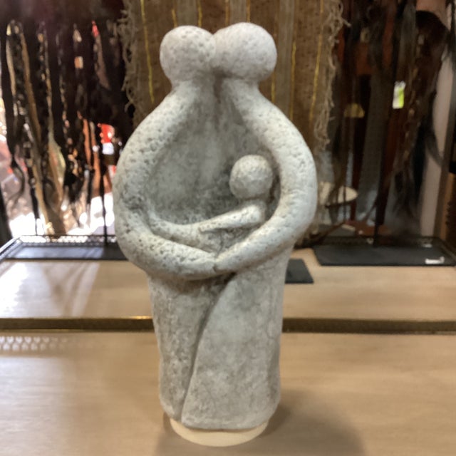 A stone sculpture of a man, woman and baby. This hand-carved wood sculpture from stone was created in Europe during the...