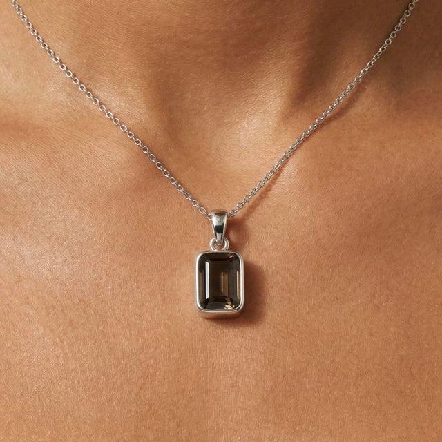 This sophisticated pendant features a rich and earthy Smoky Quartz gemstone, admired for its deep brown tones and subtle...
