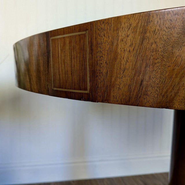 Vintage Regency-style drum table with a tooled leather top and carved pedestal base. Features a walnut-veneered top with...
