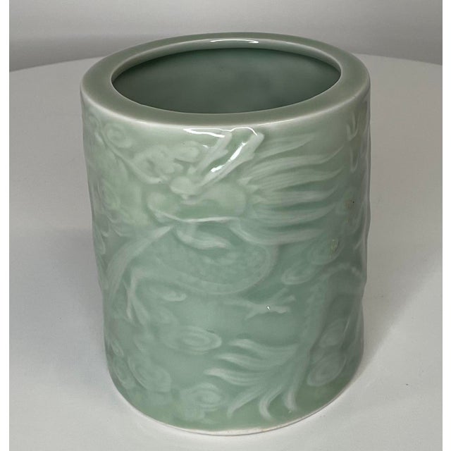 Celadon brush pot with dragon relief. Motif is soft and calming. Flowers, foliage, clouds and dragon are featured....