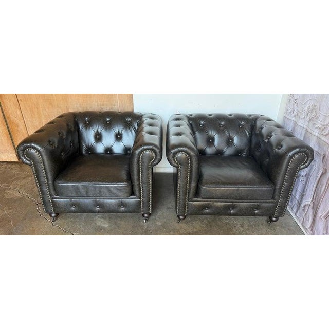 A superb and highly sought-after matched pair of classic English Chesterfield club chairs, upholstered in a deeply rich...