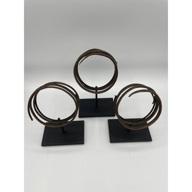 Sold as a set of 3. Spiral cuffs from Western Africa with intricate and faint hatching mounted on custom stands, providing...