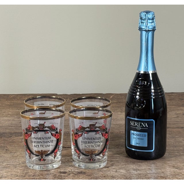 A set of four vintage apothecary-style glass tumblers decorated with antique pharmaceutical graphics reading “Liniment...